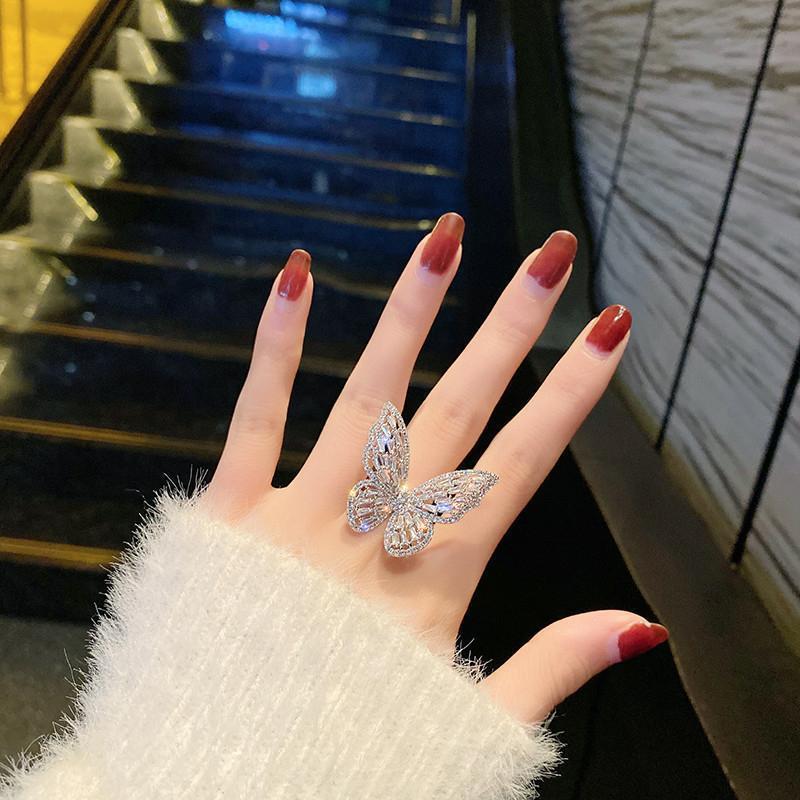 Dignified Fashion Hollow Butterfly Ring showcased on a hand with red nails, reflecting silver and diamond accents.