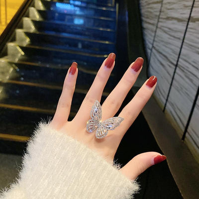 Dignified Fashion Hollow Butterfly Ring showcased on a hand with red nails, reflecting silver and diamond accents.