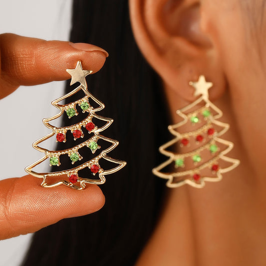 Christmas tree-shaped earrings with red and green accents held near an ear.